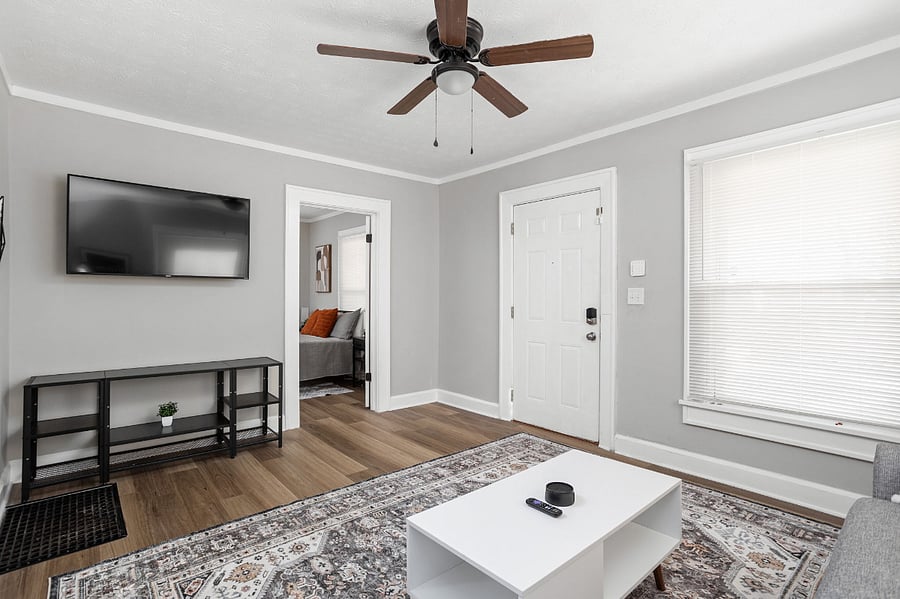Modern and mini-malistic living space with a wall-mounted TV, neutral decor, and natural light.