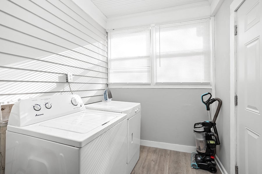 Bright and functional laundry room with a washer, dryer, and cleaning supplies.