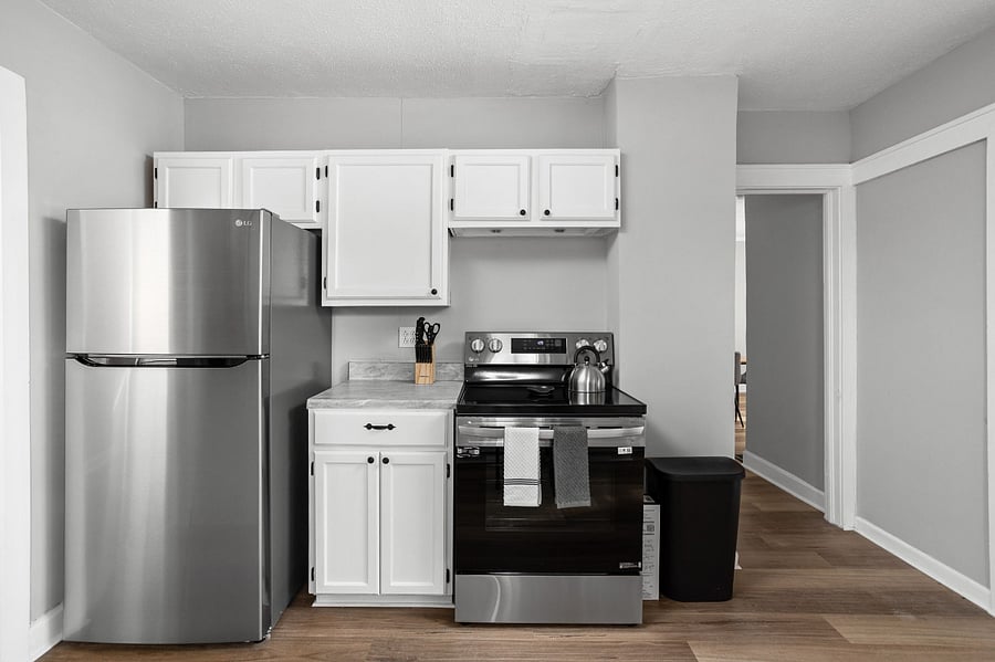 Modern kitchen corner featuring stainless steel appliances and sleek white cabinetry.
