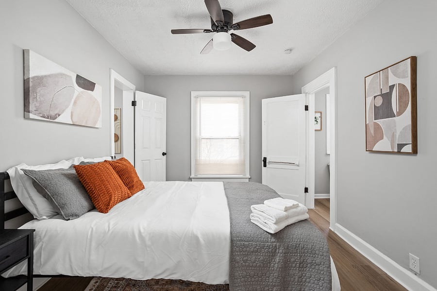 Cozy bedroom with neutral tones, modern decor, and warm accent pillows.
