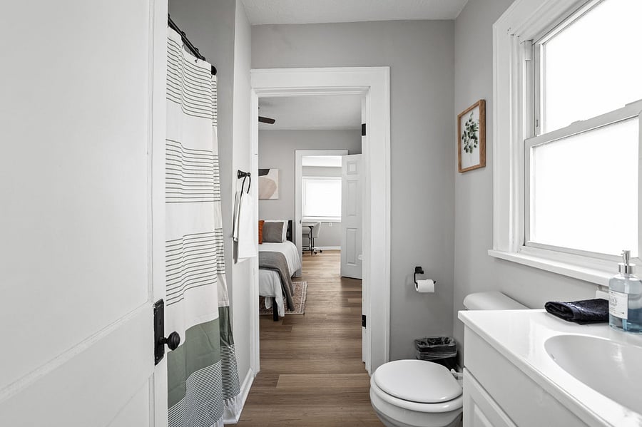 Bright and modern bathroom with a sleek vanity, natural light, and a view into the cozy bedroom