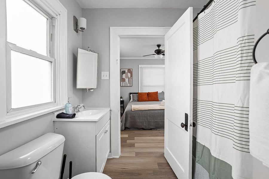 Bright and modern bathroom with a view into a cozy bedroom.