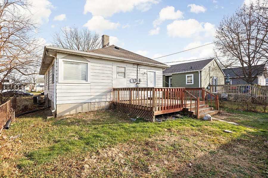 Cozy backyard with a wooden deck, open space, and neighboring homes in view.