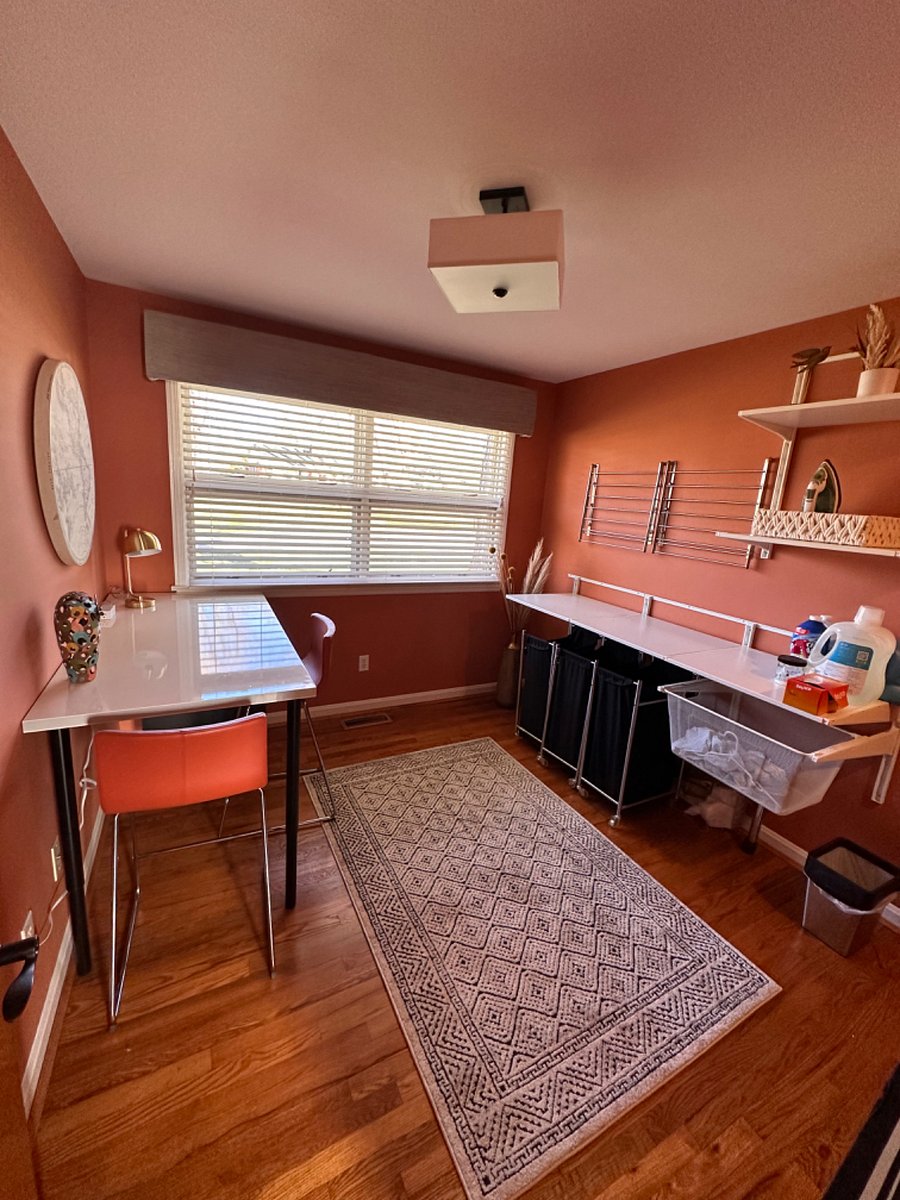 Looking towards front of house into laundry with a folding table and drying racks