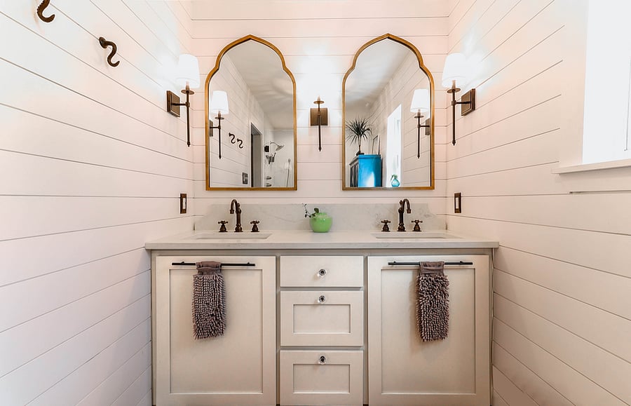 Double vanity, large walk in shower with marble flooring, and linen storage.