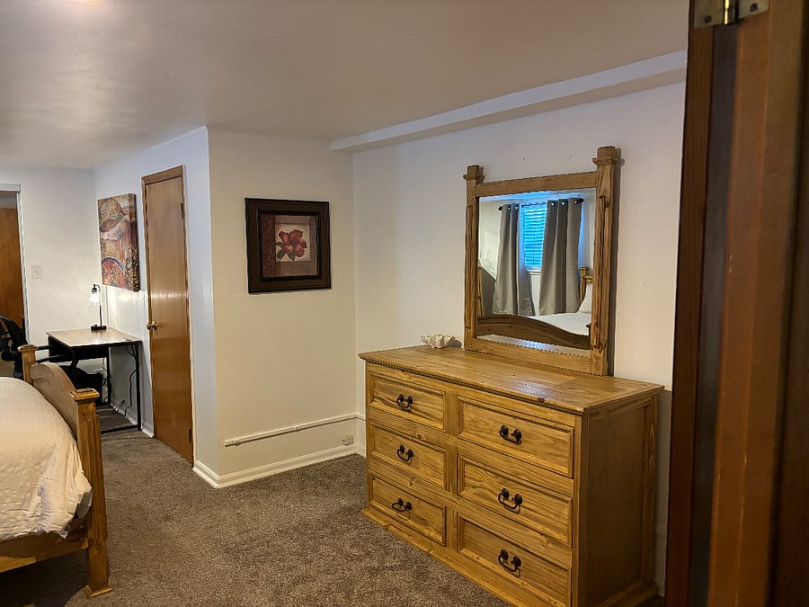 Bedroom 1. Dresser and desk with lamp. Door shown is access to full bathroom.