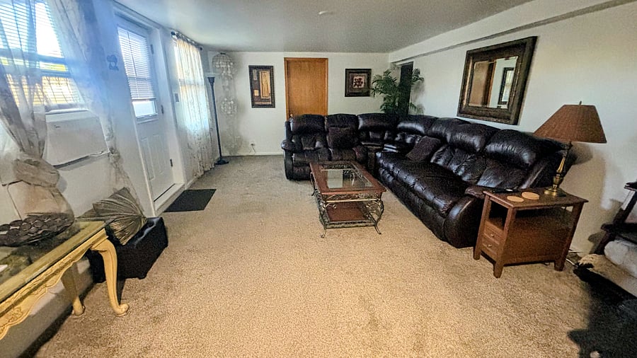 View of living room from the kitchen.  Entry into the unit is on the left.  Leather sofa has 3 recliners.