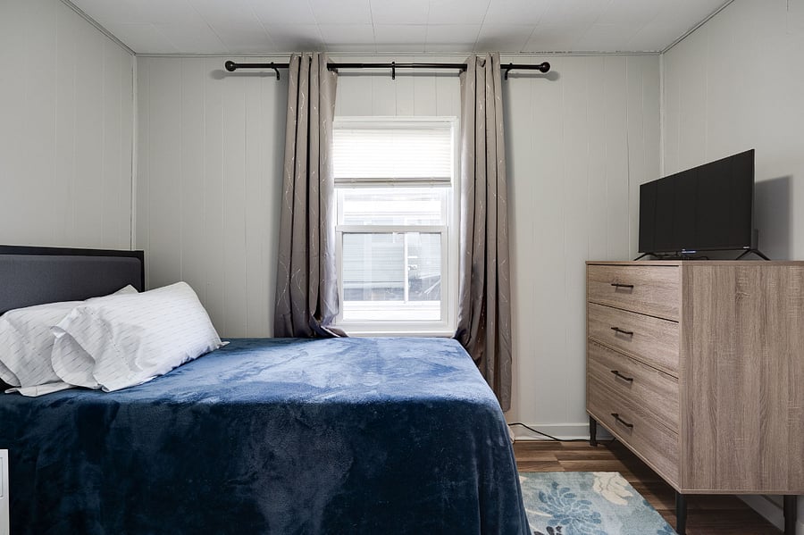 Cozy second bedroom, with Smart-TV, noise cancellation box fan, black-out curtains, dresser, closet and night table.
