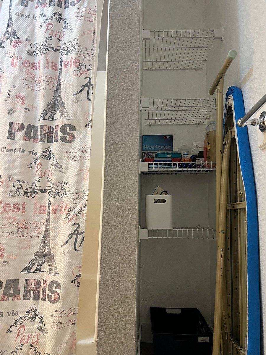Bathroom storage shelves with first aides, iron, and ironing board