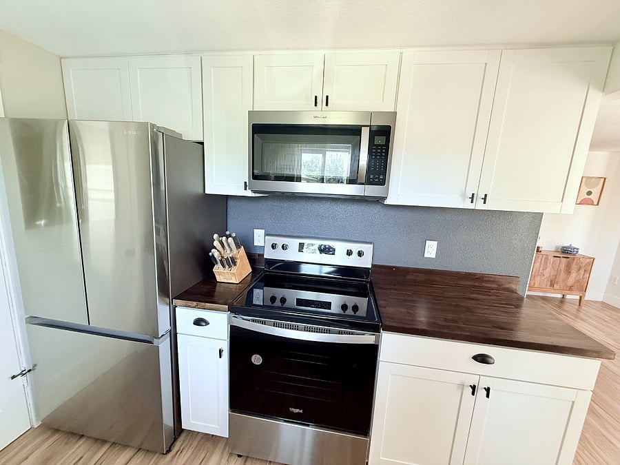New stainless steel appliances, knife block, stove, and microwave.