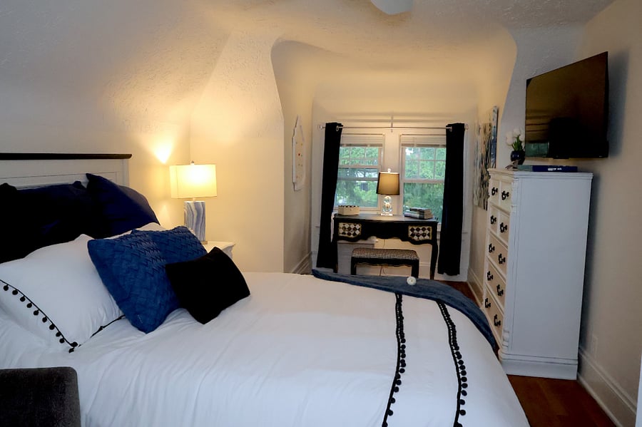 A queen bed, desk, TV, and reading chair make the bedroom both a beautiful sanctuary and a functional space