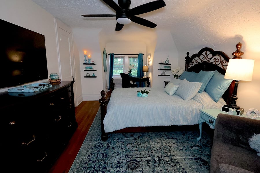 A queen bed, desk, TV, and reading chair make the bedroom both a beautiful sanctuary and a functional space