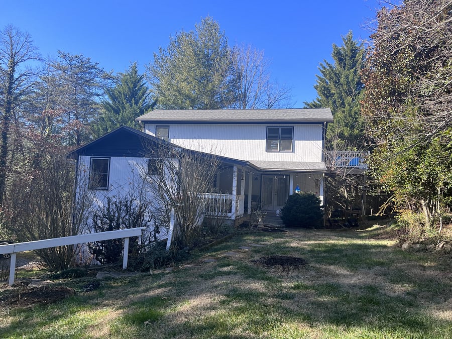 Country farmhouse with front porch. Uncovered parking is at the bottom of the path.