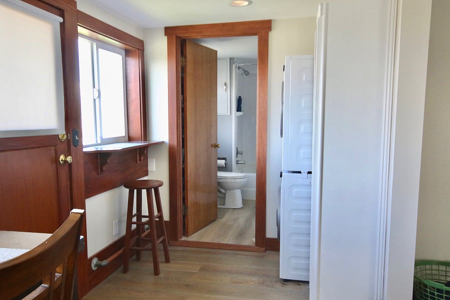Showing back door, kitchen nook seat, bathroom entrance, and washer/dryer.
