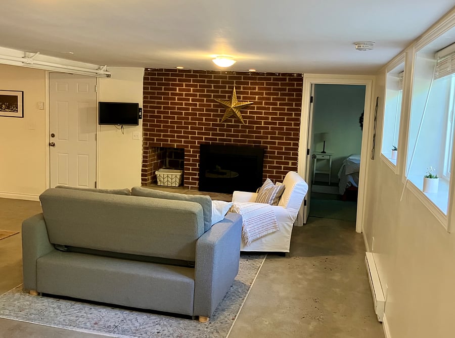 working fireplace in living room with exposed brick for a cozy vibe. smaller bedroom door off to the right.
