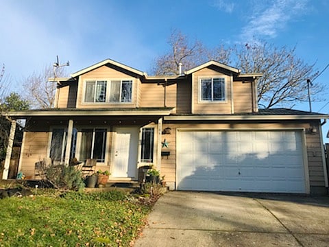 View of the front of the house with small front porch and yard situated on a quiet, Elm tree lined street. 