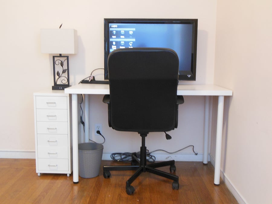 Desk with storage cabinet, chair, 32 inch monitor and lamp.