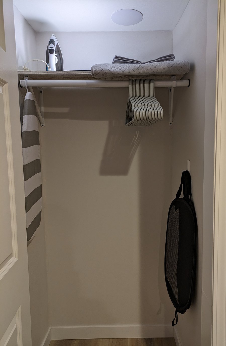 Bedroom closet with hangers, hanging laundry basket, additional storage containers, and luggage rack for tenant use.