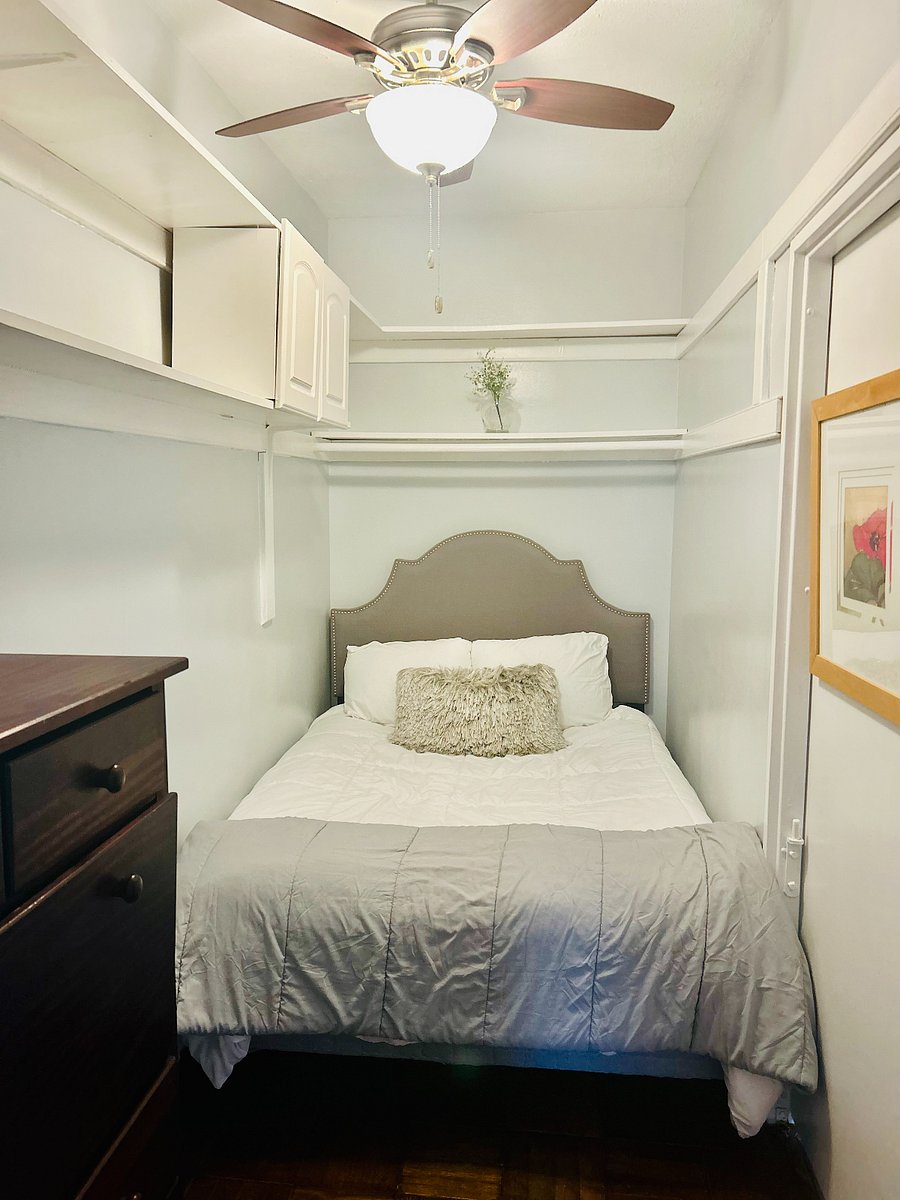 Sleeping area with double bed, dresser and ceiling fan.