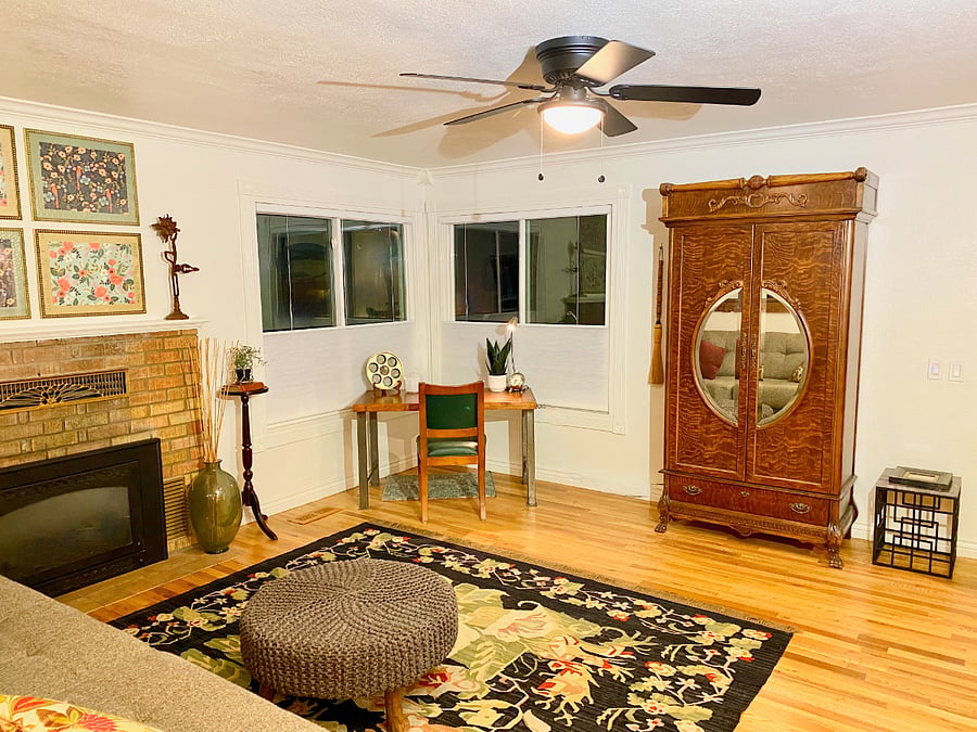 Antique armoire has a 2023 Roku TV hidden inside.  Large corner windows look out onto the street with up/down cellular shades for privacy choices at the desk.