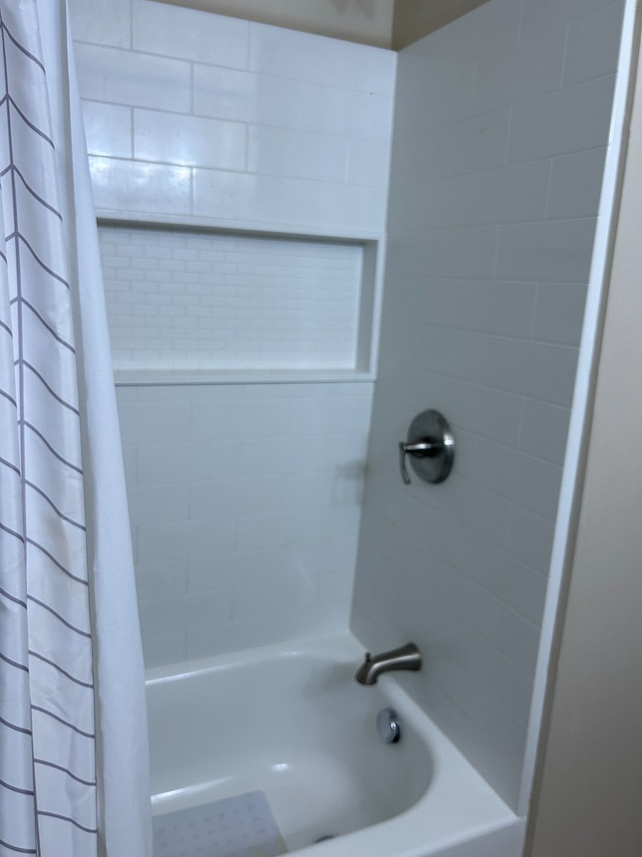Full bathtub with shower. New tub surround offers built in shelves!