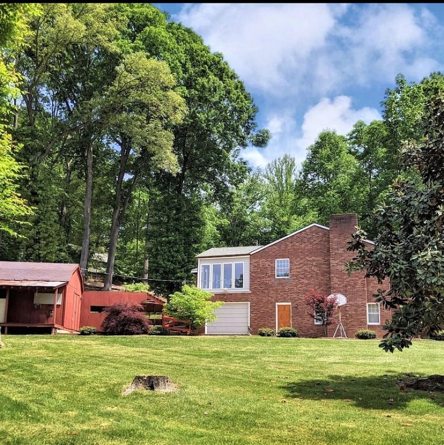 Side view of house from side yard, including very large driveway and storage barn