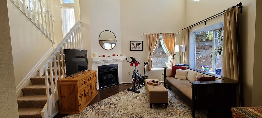 Cozy living room includes smart TV, electric fireplace, exercise bike and yoga mats, and warm natural light!