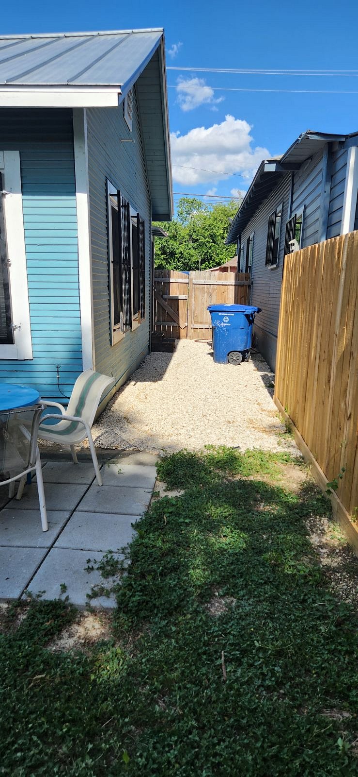 Looking from back yard towards back door and gate to driveway. Back patio with table and chairs and grill.