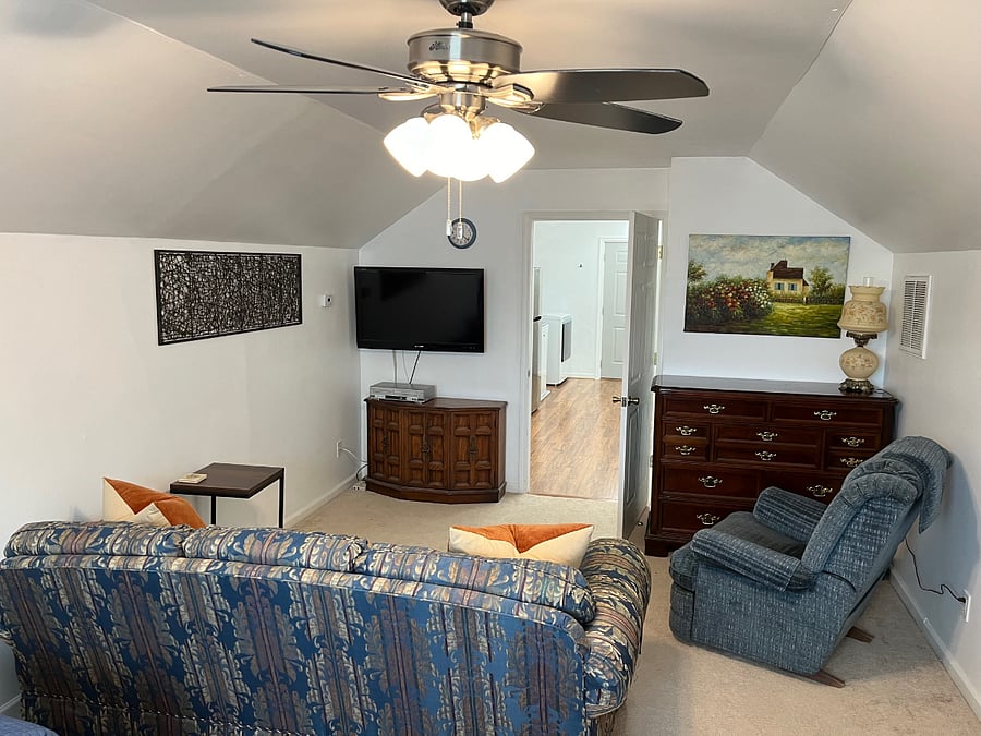 Living area with sofa, recliner, TV and dresser.