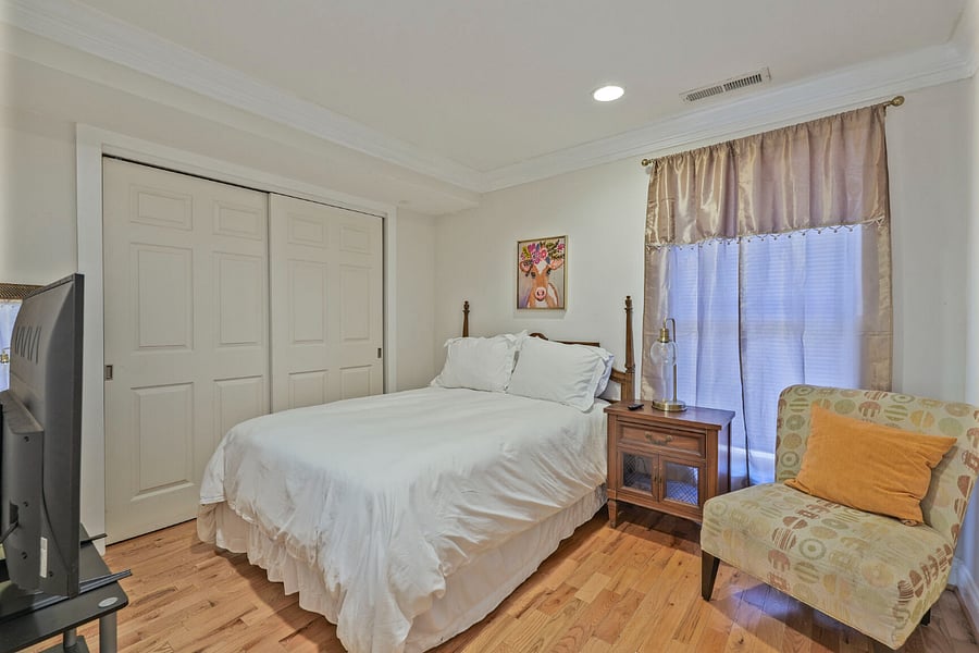2nd bedroom with full bed, spacious closet, 47 inch smart tv, room darkening shades with sitting chair.
