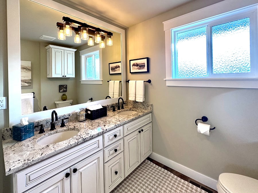 The lovely main bathroom features all new custom cabinetry, granite counters, oiled-bronze plumbing and modern lighting. This spacious bathroom with its double sink vanity and double hang towel bars can easily accommodate 2-3 guests.