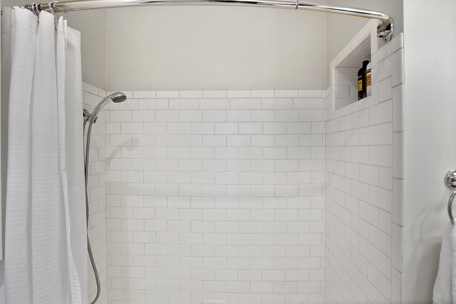 Tiled shower / cast iron tub combo. Niche for shampoo, conditioner.