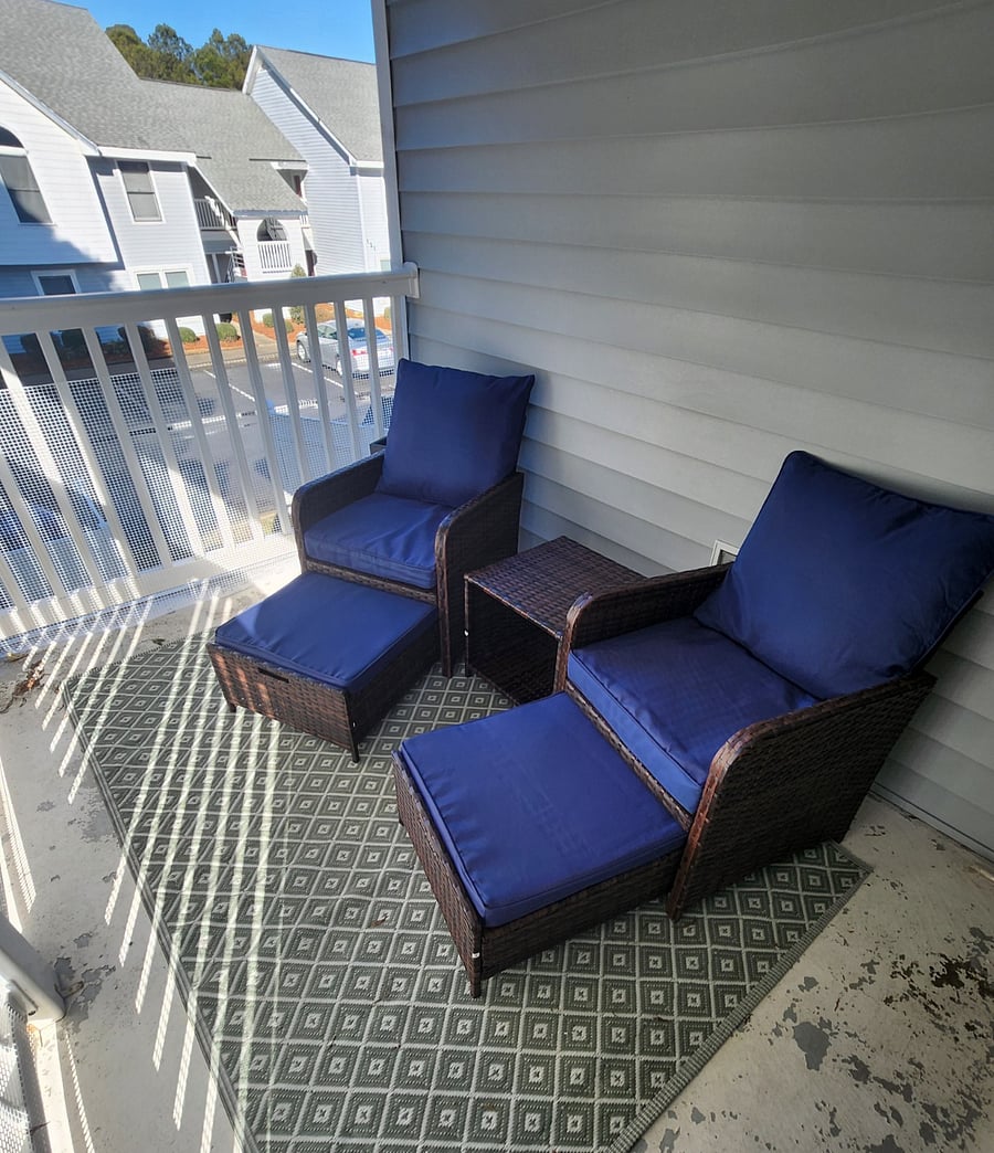 Balcony with sitting area, ceiling fan and roll down shades.
