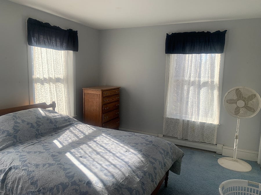 The blue bedroom with a double closet, three windows, and a double bed.