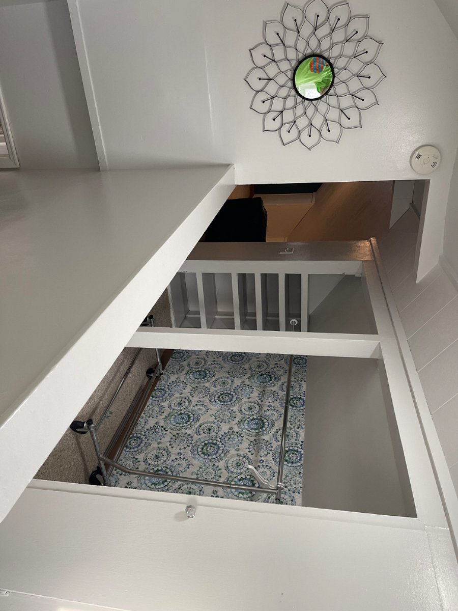 Upstairs at top of stairs. View of closet. There are shallow shelves on left, and built-in shelving with a door on the right side.