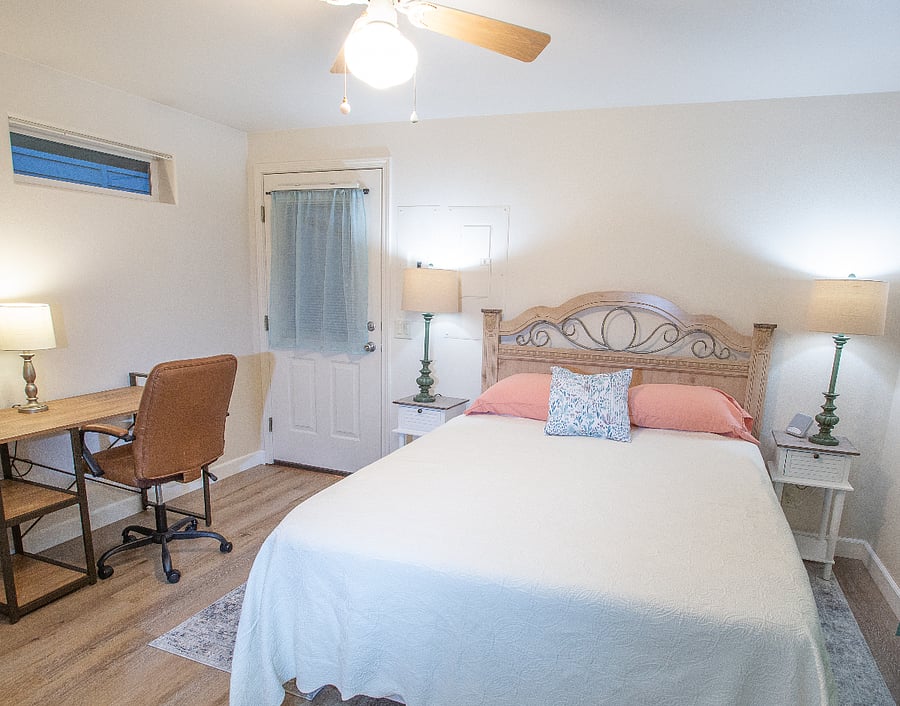 Bedroom features a desk with chair for working and a door to the back porch of the unit. (picture taken before wall decor was hung)