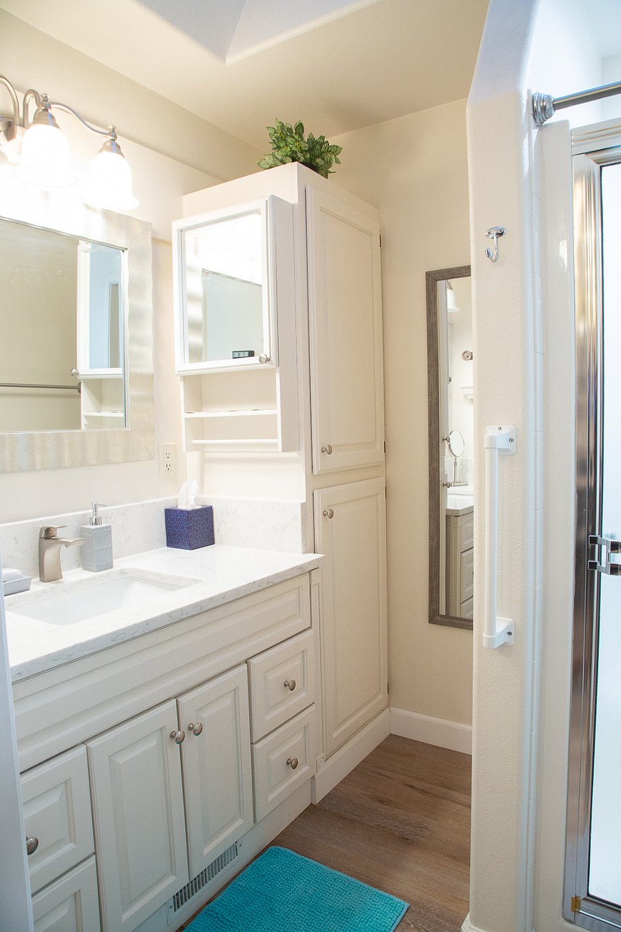 Bathroom has updated countertops and lots of storage. There is a full-size mirror and shelving.