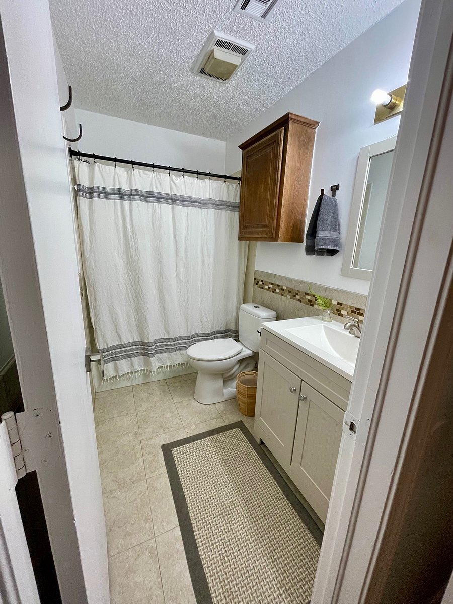 Shower-over-tub, 30" vanity with storage, hooks for towels, and a cabinet with additional storage over the toilet.