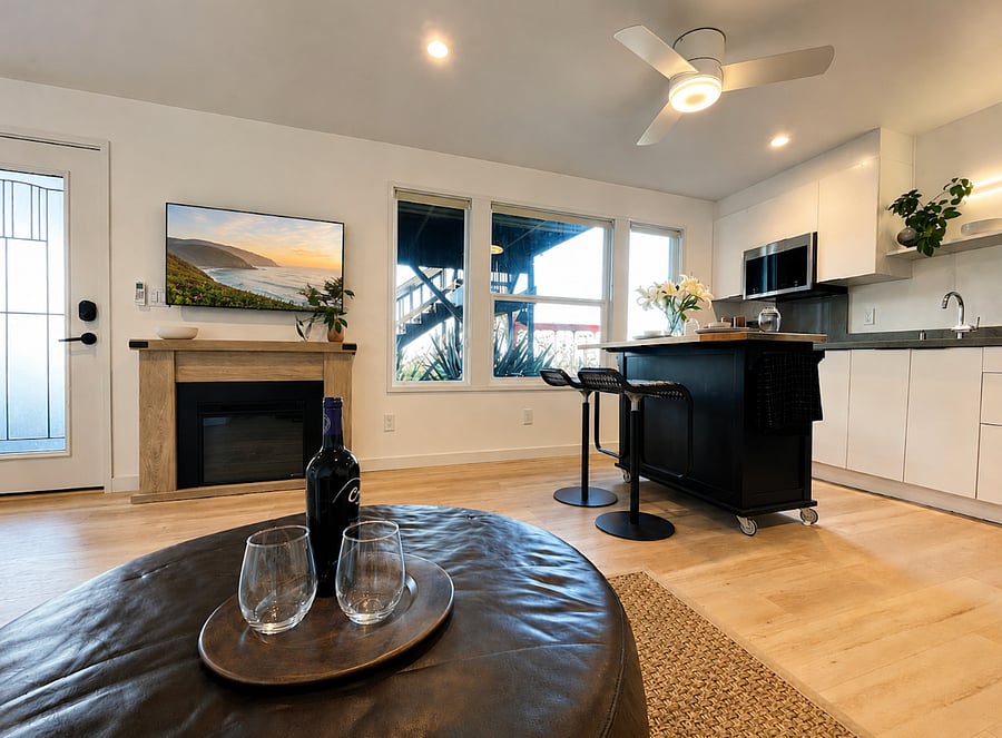 Light-filled open living space with warm natural light, cozy lounge seating, fireplace, and a modern kitchen that creates a calm and comfortable place to unwind.