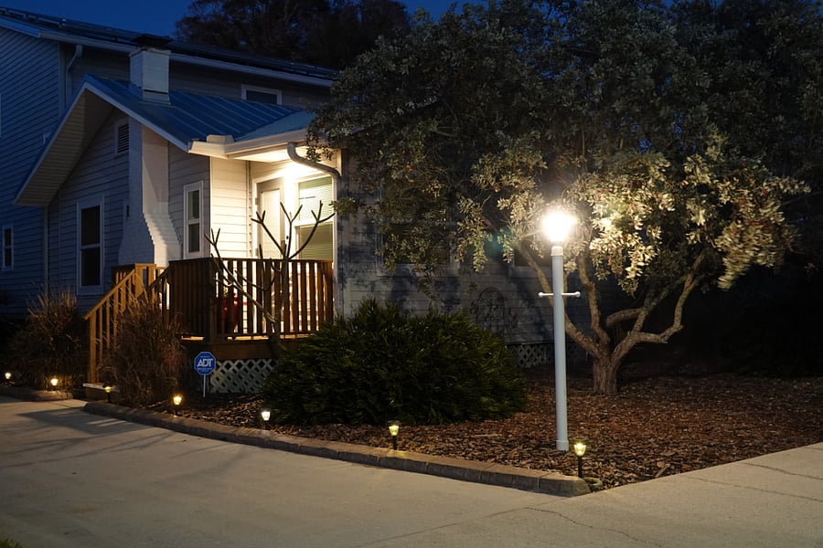 The entrance is well-lit at night by a pole lantern, driveway solar lights, and an overhead LED porch light.