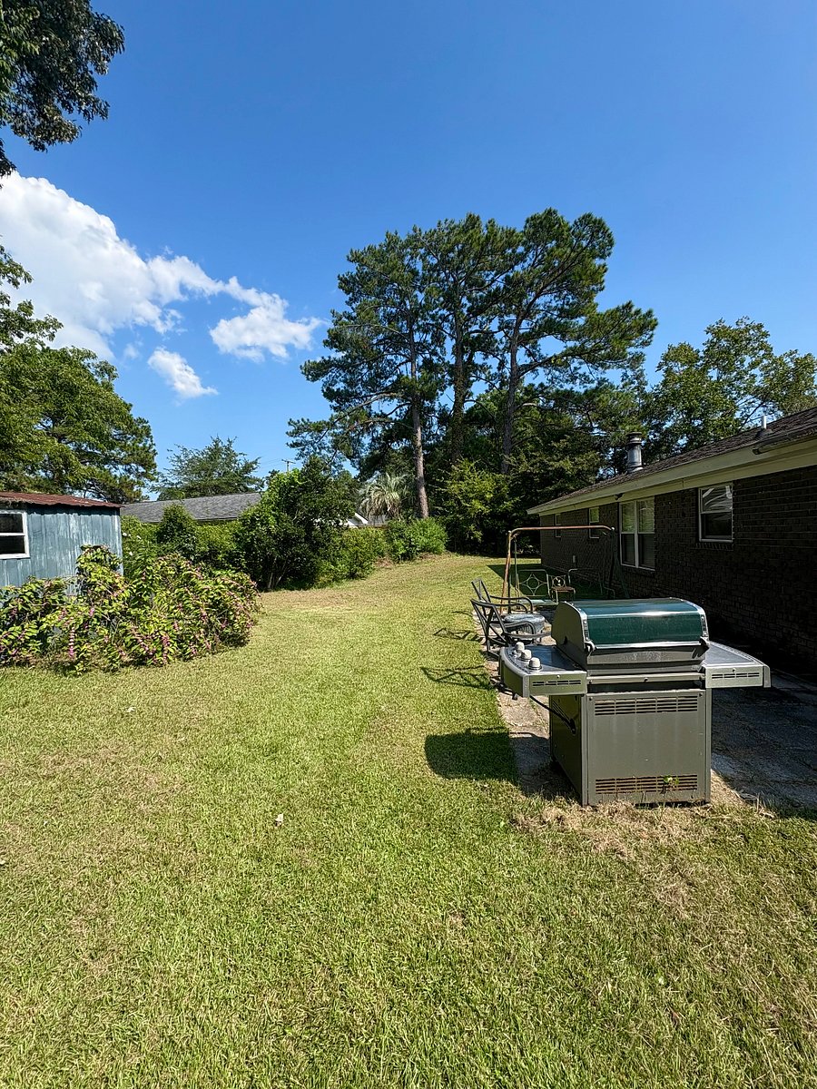 Sunny spacious backyard with patio, grill, chairs and swing