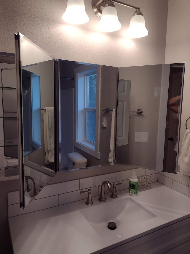 Bathroom counter showing tri-mirror "medicine" cabinet.