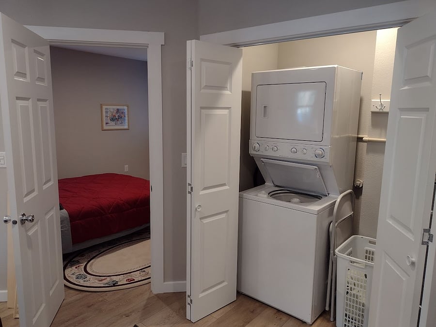 Stacking clothing washer/dryer and view into bedroom from Living room