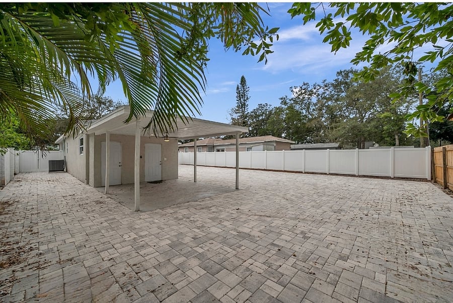 Large fenced in backyard with covered carport.