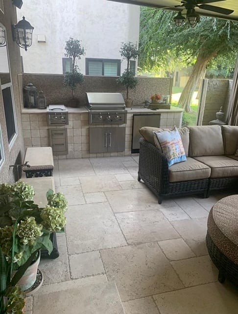 Outdoor covered patio with BBQ, mini fridge, ice coolers, and sectional seating.