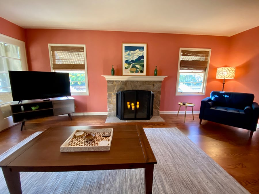 Living room with 50" TCL Roku smart TV, decorative fireplace, sofa bed, seating area with bookshelf and French doors to the sunporch.
