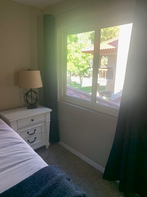 2nd bedroom bedside table and window looking out to greenbelt