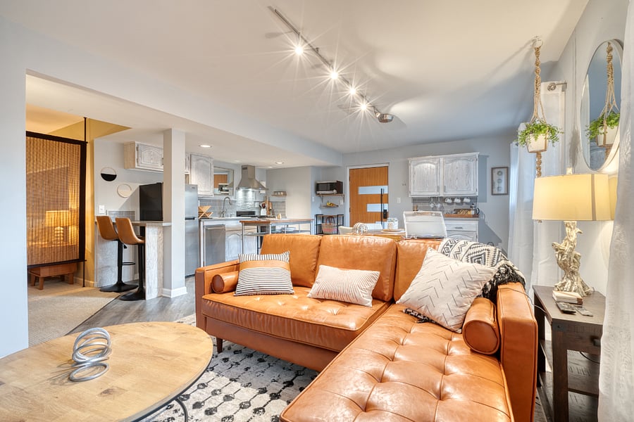 Your lounging space: equipped for you and guests if you see fit. Real leather sofa/chaise, side table with charger, two-person bar at the end of kitchen. Television is on the wall just to the left.