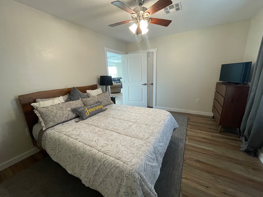 Main bedroom with a queen bed. Bed has a new mattress. The open door steps out into the dining area and the closed door leads into the main bathroom. 