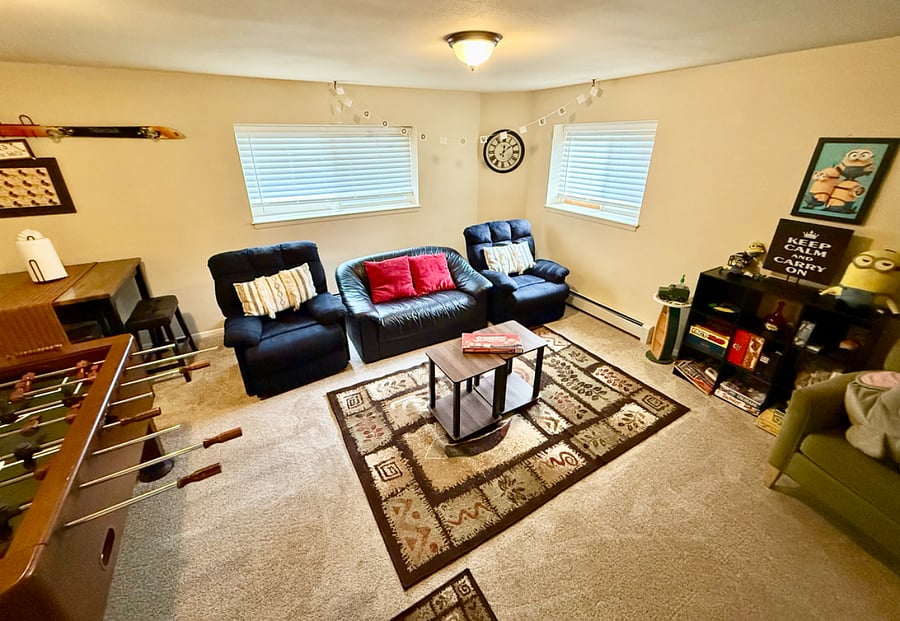 Living room in basement with seatings, board games, foosball table, and TV